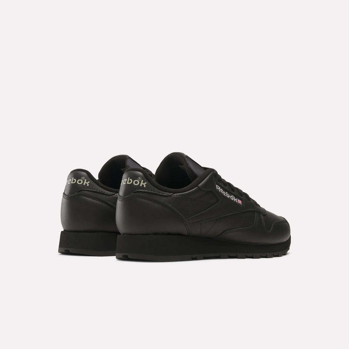 A pair of Reebok Classic Leather Shoes with a black leather upper are displayed on a white background, angled to reveal retro Reebok branding on the heels and sides.