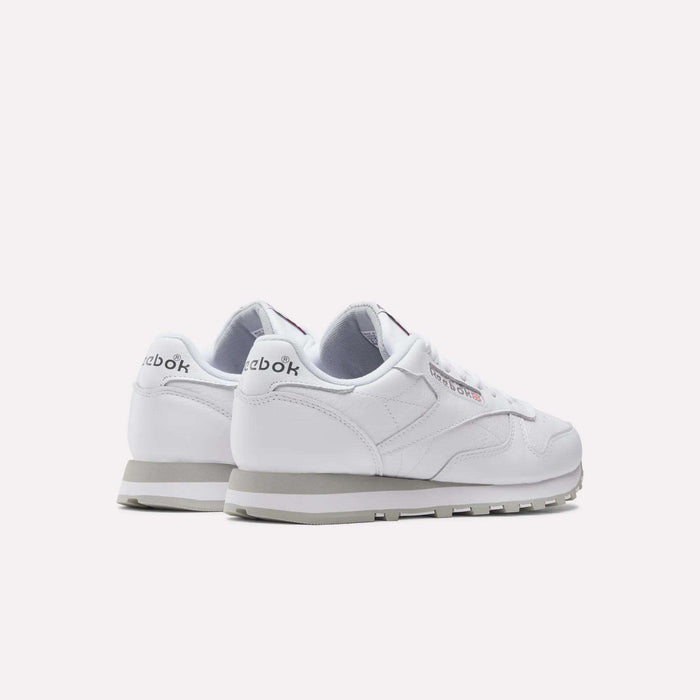 A pair of Reebok Classic Leather Shoes with white uppers and grey soles, displayed at an angle to show the back and sides. The Reebok logo appears on the heel and side, highlighting these stylish retro sneakers.