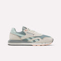 The Reebok Classic Nylon 89 Shoes feature light blue and beige suede and mesh panels, white laces, a gray and white cushioned midsole, light orange details on the outsole, all shown against a plain white background.