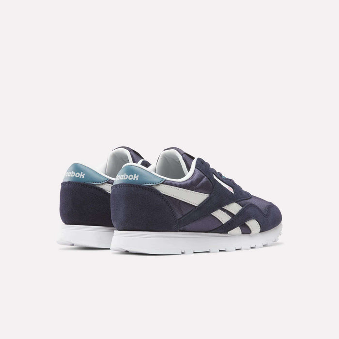 A pair of Reebok Classic Nylon Shoes - Big Kids in navy blue and white, accented with light blue on the heel, are displayed against a white background. Shown from the back and side angles, these boys’ shoes emphasize their sporty and stylish design.