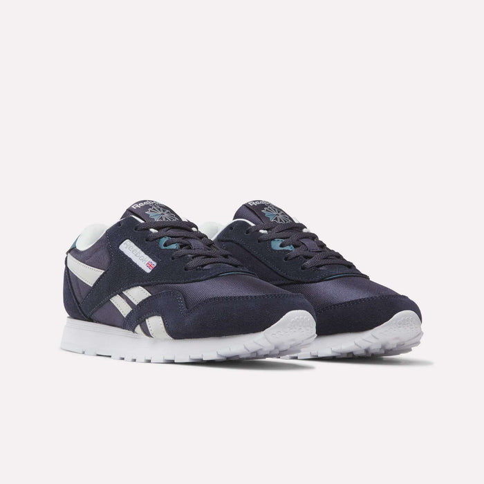 A pair of Reebok Classic Nylon Shoes - Big Kids in navy blue and white, showcasing white soles, side stripes, and logo accents, set against a light background.