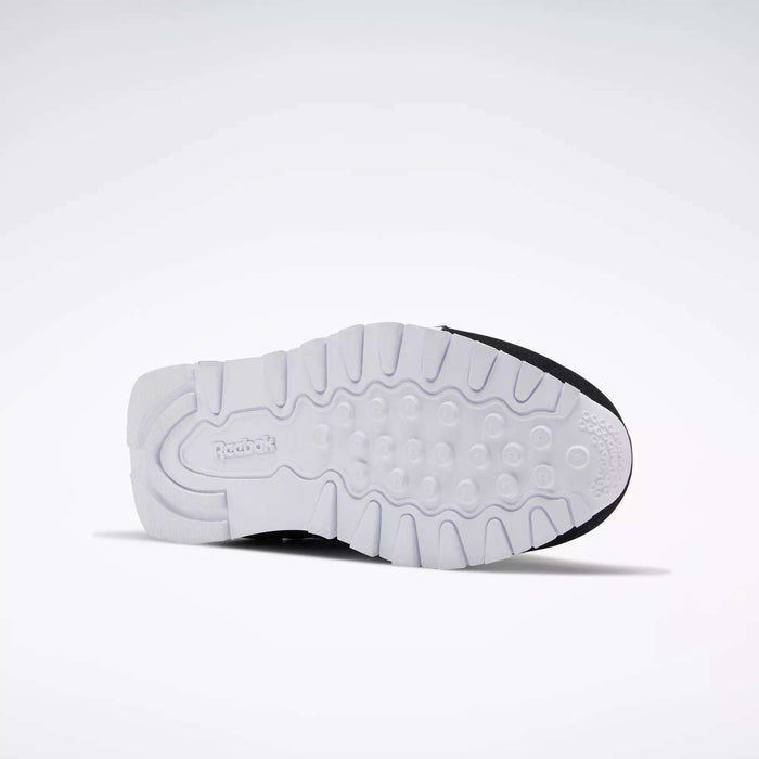 The image displays the sole of Reebok Classic Nylon Shoes - Big Kids facing upward, featuring a white, textured grip pattern and the Reebok logo by the heel. Its minimalist design pays tribute to classic 80s styles against a plain light gray background.