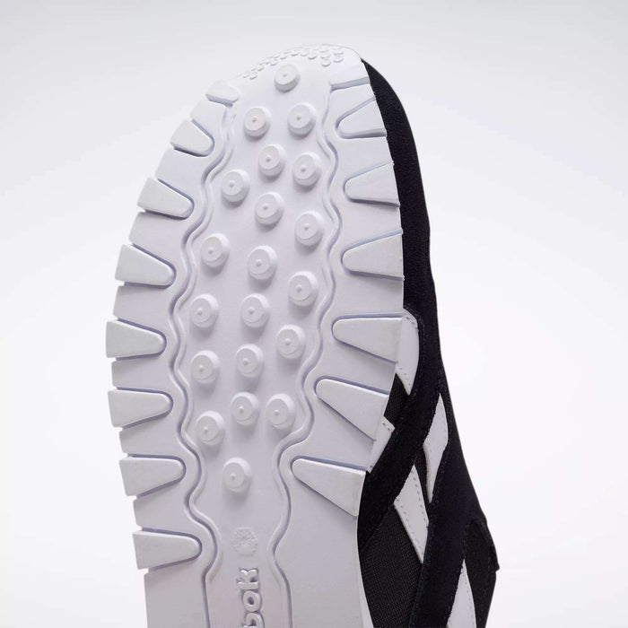 Close-up of the outsole on Reebok Classic Nylon Shoes - Big Kids, showing textured tread, circular grips, and angular edges on a white rubber sole inspired by 80s running shoes.