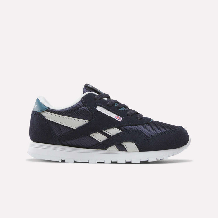 A Reebok Classic Nylon Shoe for little kids in Dark Indigo, New Grey 1, and Midnight Tide, featuring a white sole, side stripe design, and mesh accents. This boys’ sneaker is shown from the side against a plain white background.