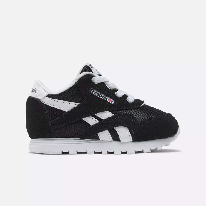 The Kids' Classic Nylon Shoes - Toddler by Reebok feature a black and white suede and nylon upper, white laces, a white sole, and signature Reebok logos on the side and tongue, shown against a plain white background.