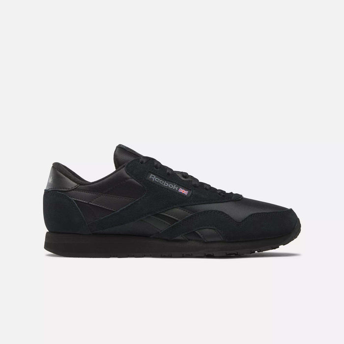The Men's Classic Nylon Shoes by Reebok feature a low-profile, lace-up design in black with a nylon upper and the Reebok logo plus Union Jack flag on the side, shown against a plain white background.