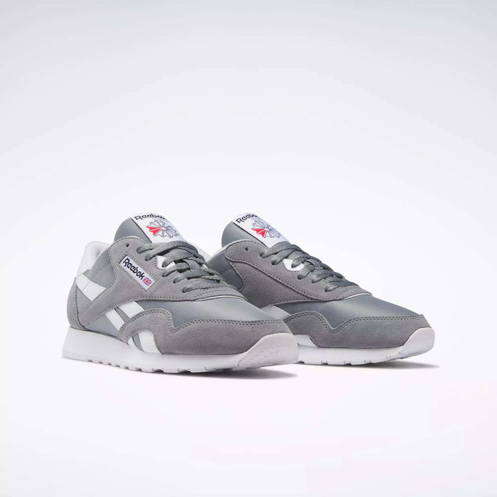 The Reebok Men's Classic Nylon Shoes are light gray everyday sneakers with white accents and laces, a durable nylon upper, and the Reebok logo on the side and tongue, shown against a plain white background.
