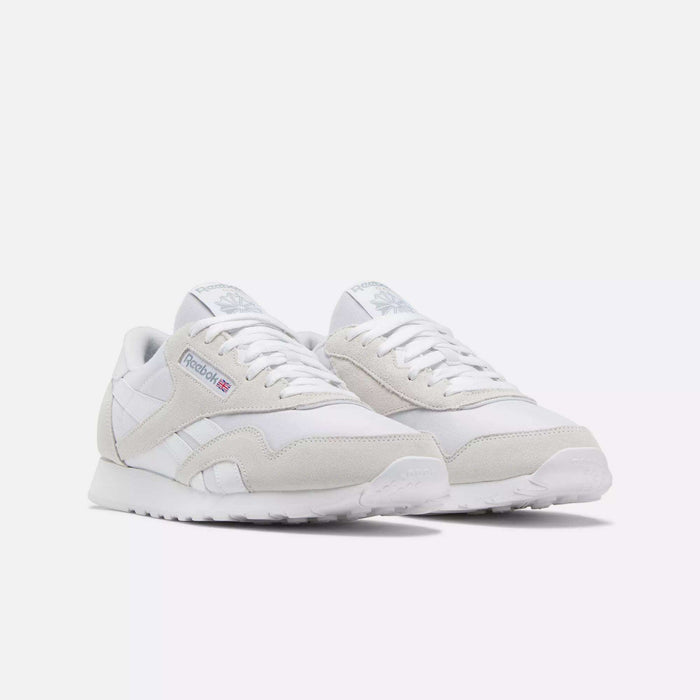 The Reebok Men's Classic Nylon Shoes feature white uppers with light gray suede accents, white laces, and the iconic Reebok logo on the side—perfect everyday sneakers for a clean, classic look.