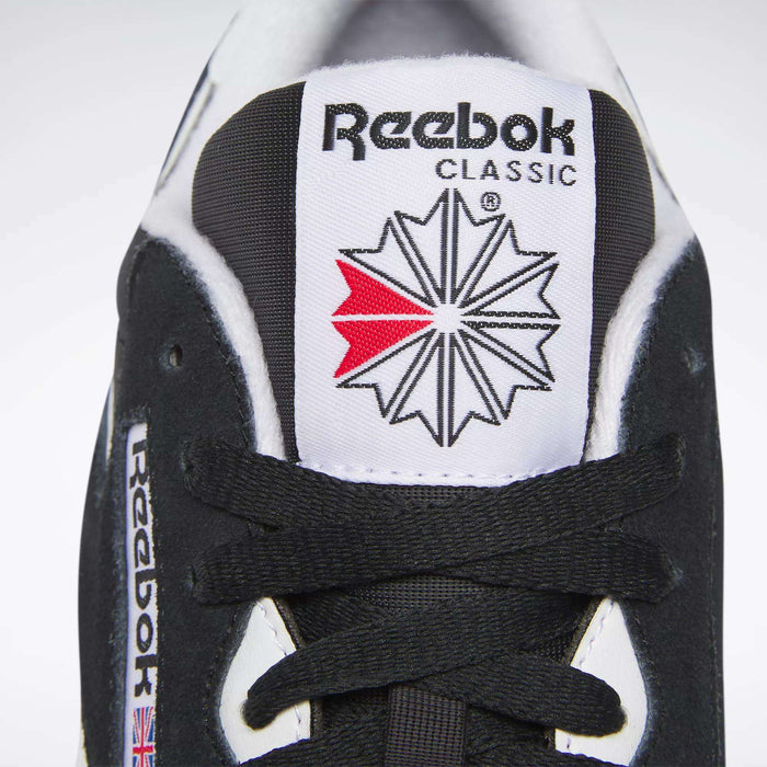 Close-up of the tongue of a black Reebok Men's Classic Nylon Shoe, highlighting the Reebok logo, red and grey starburst, black laces, and a small Union Jack flag—signature details of these classic sneakers.