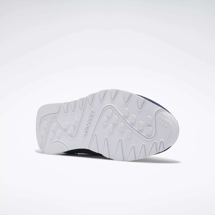 The Reebok Men's Classic Nylon Shoes are shown on their side against a plain light background, displaying the white textured sole with tread patterns and Reebok branding, emphasizing the grip of these classic everyday sneakers.