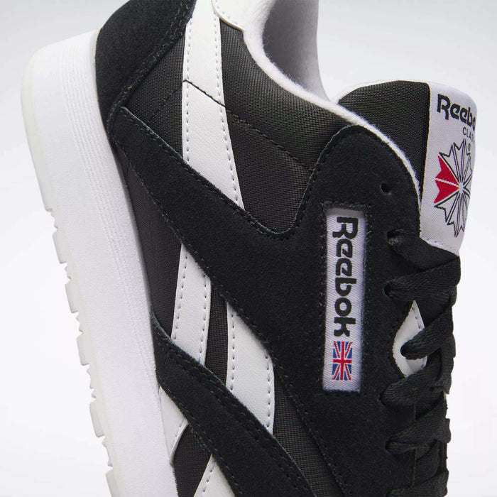 Close-up of Men's Classic Nylon Shoes by Reebok, featuring the logo, Union Jack flag, black laces, and a white sole—these timeless sneakers are perfect for daily wear.