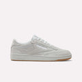 A side view of the Reebok Club C 85 Shoes in light grey suede with white laces, a slightly off-white sole, and a light brown gum bottom. The Reebok logo is displayed on the side and heel.
