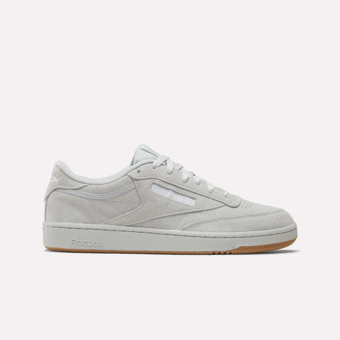 A side view of the Reebok Club C 85 Shoes in light grey suede with white laces, a slightly off-white sole, and a light brown gum bottom. The Reebok logo is displayed on the side and heel.