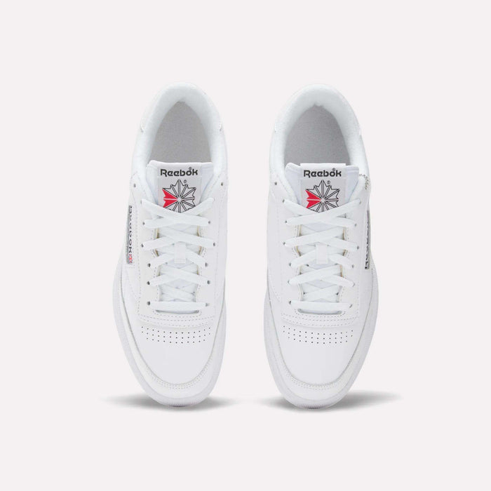 A top view of the Reebok Club C 85 Shoes in white leather, showcasing tennis-inspired toe perforations, white laces, and the Reebok logo with a red and gray starburst on the tongue.