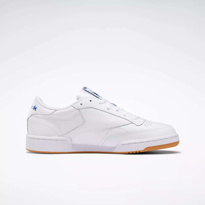 The Reebok Club C 85 Shoes are low-top white leather sneakers with a simple design, white laces, gum sole, and subtle blue branding on the heel and tongue, shown against a plain white background.
