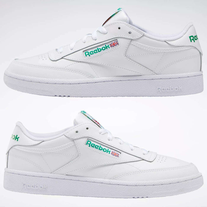 Two white Reebok Club C 85 Shoes are shown in profile, featuring green logos and Union Jack flag details on the sides, set against a plain white background to highlight their classic, tennis-inspired design.