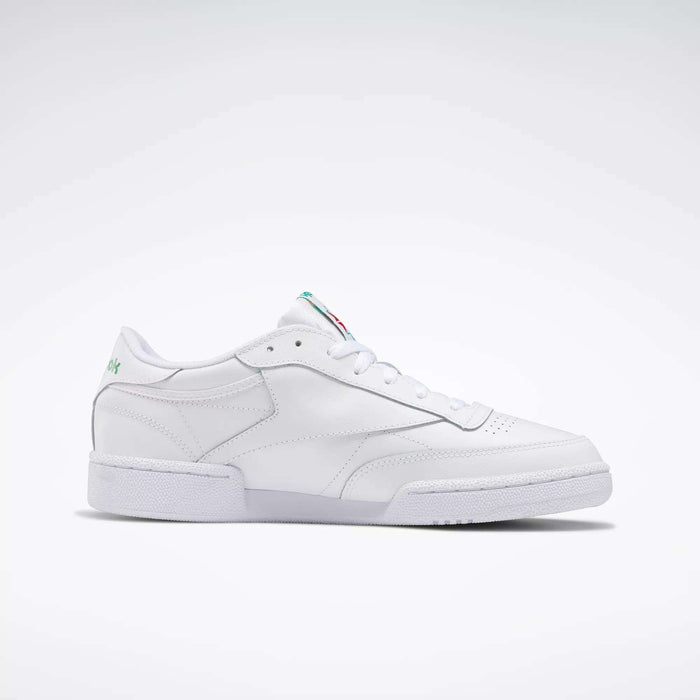 The Reebok Club C 85 Shoes are white leather low-top sneakers inspired by tennis, featuring a simple design with a flat sole and subtle colored accents on the tongue and heel, shown against a plain white background.