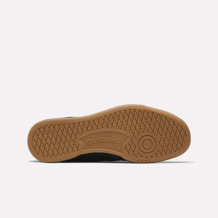 The image shows the brown rubber outsole of the Reebok Club C 85 Shoes, featuring a circular pattern by the heel, a herringbone tread, and an embossed Reebok logo at the midfoot.