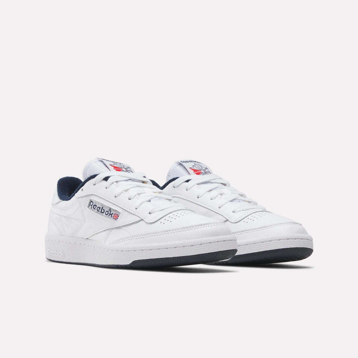 A pair of white Reebok Club C 85 Shoes with navy and red accents, showing the Reebok logo and British flag on the sides and tongue. Classic tennis-inspired style, displayed against a plain white background.