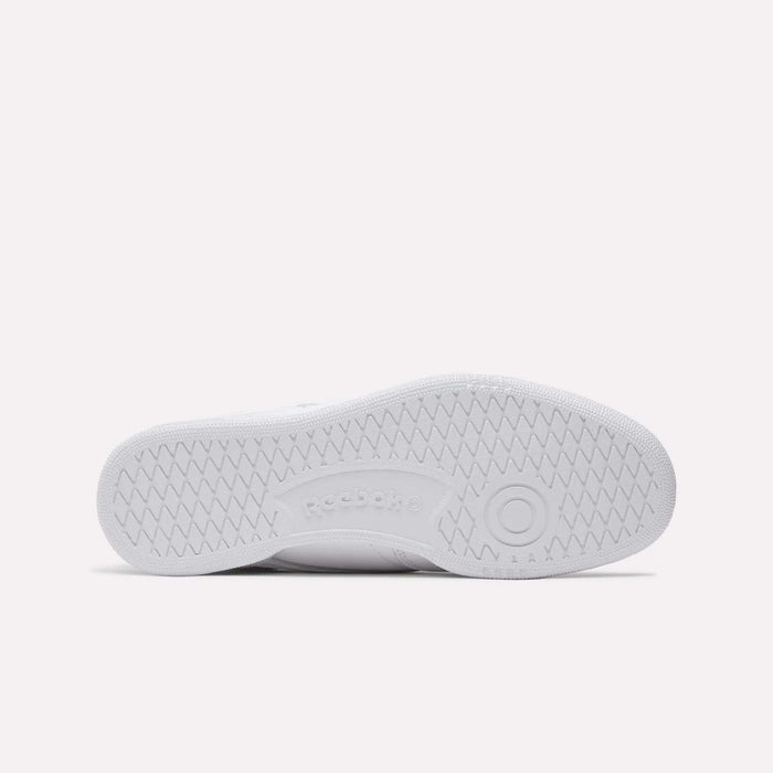 The image displays the bottom view of a Reebok Club C 85 Shoes sole, featuring a white herringbone tread pattern and center-embossed Reebok logo, emphasizing its classic tennis-inspired design.