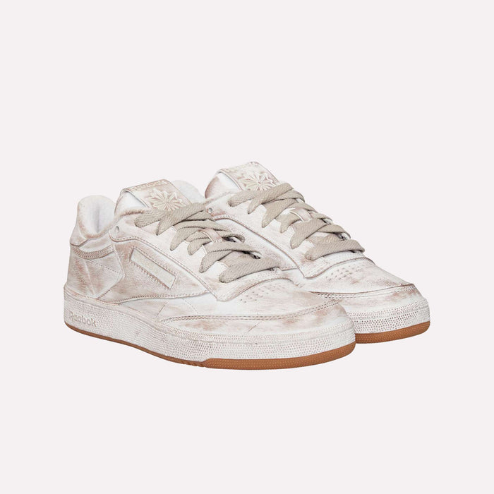 A pair of Reebok Club C 85 Vintage LTD Shoes in a worn-look off-white finish, featuring light brown laces and gum soles, are placed side by side on a plain white background—showcasing the timeless appeal of this classic lifestyle tennis shoe.
