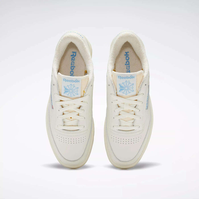 A pair of Club C 85 Vintage Shoes by Reebok, seen from above, with an off-white leather upper, light blue Reebok branding on the tongue and side, cream laces, and a soft textured inner lining.