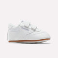 Reebok Kids' Club C Crib Shoes for toddlers feature a soft white leather upper, dual hook-and-loop closures, subtle stitching, and a light brown rubber sole, displayed against a plain white background.