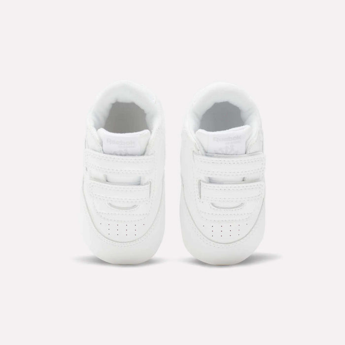 The Reebok Kids' Club C Crib Shoes for babies and toddlers are small, white shoes with hook-and-loop closures and a soft leather upper, shown from above on a plain light background.