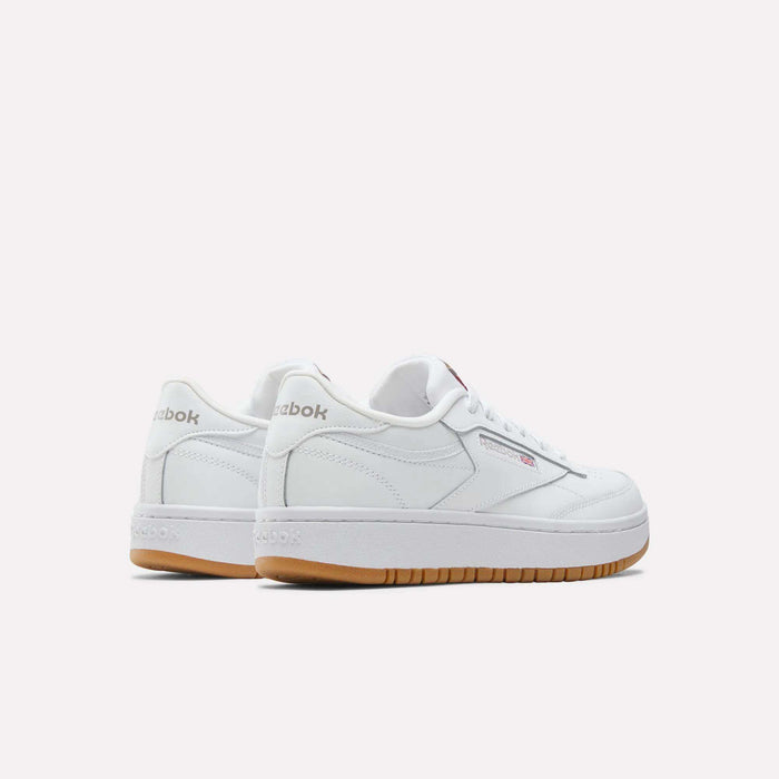 The Reebok Club C Double Shoes for big kids feature a white leather upper and gum soles, with the Reebok logo on the heel and side. Shown from the side and back against a light background—ideal for girls' shoe collections.