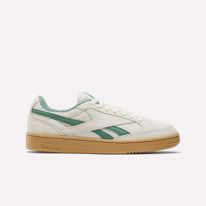 Side view of the Reebok Club C Grounds 70 Shoes in white with green accents and logo, crafted from premium suede with a light brown rubber sole. This retro, ‘70s-inspired sneaker is shown against a plain white background.