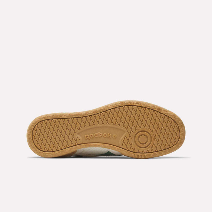 The image shows the bottom view of the Reebok Club C Grounds 70 Shoes with a gum-colored herringbone rubber sole, circular grip at the toe, and Reebok branding—reflecting '70s-inspired details from classic Reebok designs.