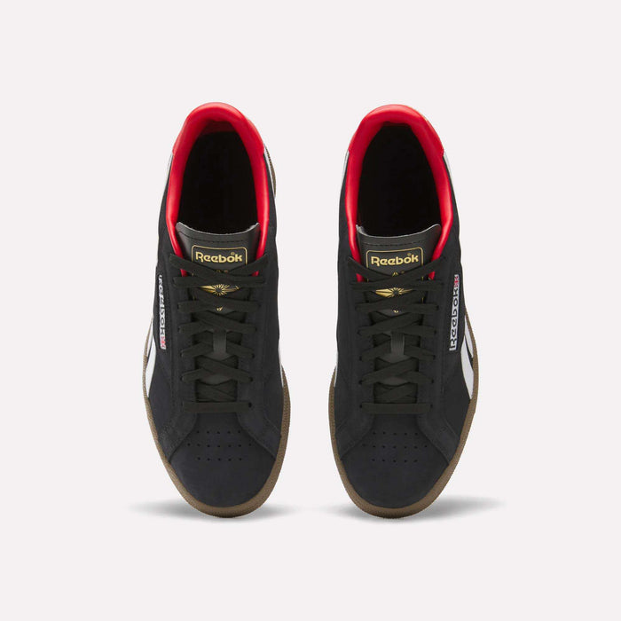 A pair of Reebok Club C Grounds UK Shoes in black with white side stripes, gold and red accents, black laces, and gum soles are shown from above on a white background—a perfect classic tennis-style casual shoe.