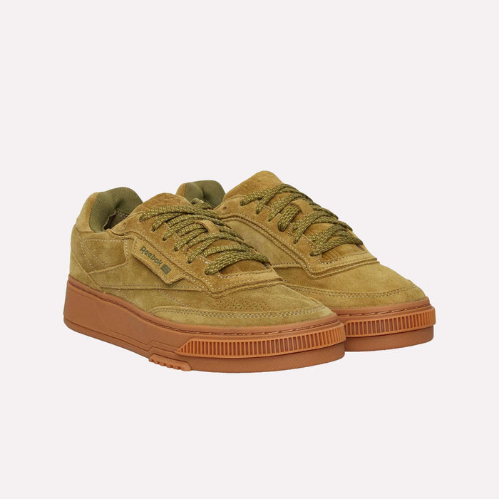 A pair of Reebok Club C LTD Shoes in tan suede, featuring olive green laces and a light brown rubber sole, displayed on a plain white background—an iconic lifestyle classic inspired by the timeless tennis shoe silhouette.