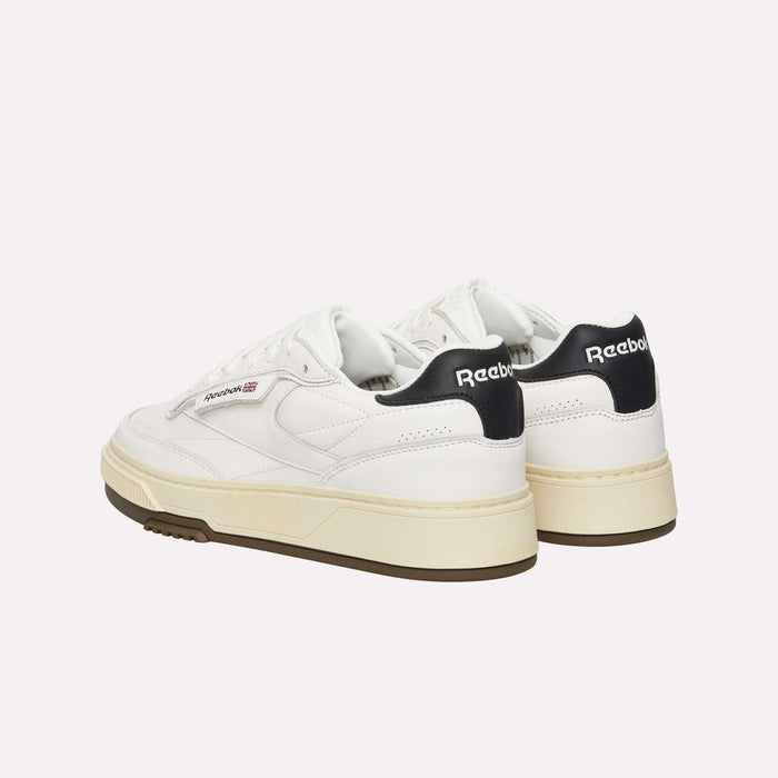 A pair of Reebok Club C LTD Shoes in white, featuring cream-colored soles and black accents on the heel, shown from the back and side against a plain background—offering a fresh interpretation of this lifestyle classic.