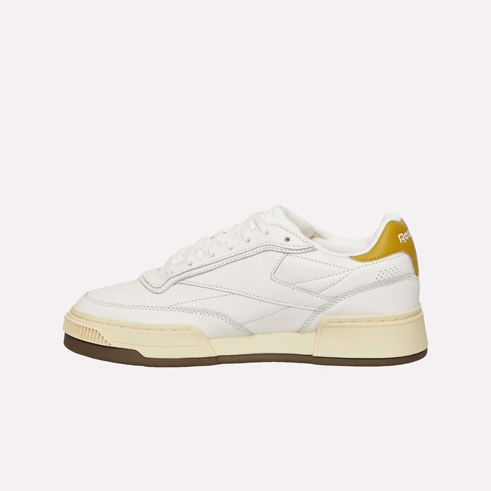 Introducing the Reebok Club C LTD Shoes—a white casual sneaker inspired by the iconic Club C. This lifestyle classic features tan and brown sole accents, a mustard yellow heel tab, crisp white laces, and visible stitching for a timeless look.