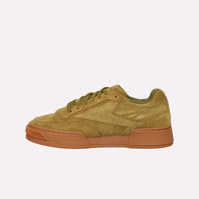 The Reebok Club C LTD Shoes feature tan suede uppers with green accents and matching green laces, set atop a thick brown rubber sole. Displayed in a side profile against a plain white background.