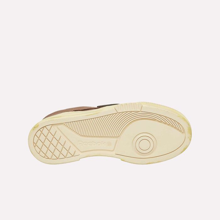 The image shows the beige sole of a Reebok Club C LTD Shoe, viewed from the bottom, featuring the Reebok logo and a textured traction pattern with curved lines and a grid section—a true lifestyle classic.