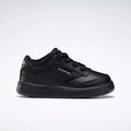 A side profile of the Reebok Kids' Club C Shoes for babies and toddlers is shown against a white background, featuring black soft leather, black laces, detailed stitching, and a small Reebok logo with British flag on the side.