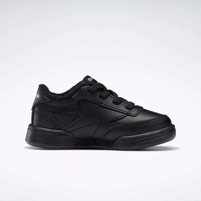 A single black Reebok Kids' Club C Shoe for babies and toddlers, featuring soft leather, black laces, and stitching details, is displayed in side profile against a plain white background.