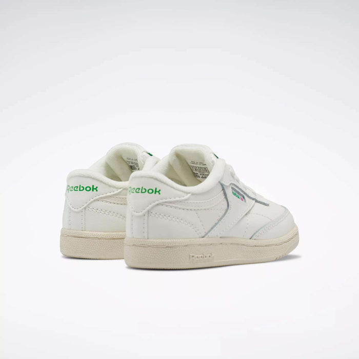 A pair of Reebok Kids' Club C Shoes for babies and toddlers with green logo accents, off-white soles, and an iconic ’80s low-top style. Positioned side by side on a white background, these sneakers add a retro touch.