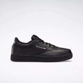 The Kids' Club C Shoes – Grade School by Reebok are black low-tops with soft leather uppers, black laces, a black sole with high-abrasion rubber outsole, plus the Reebok logo and Union Jack on the side, shown on a light background.