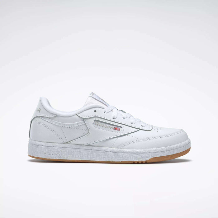 The Reebok Kids' Club C Shoes - Grade School feature soft white leather uppers, a gum sole, side branding, and perforated accents, displayed on a plain light gray background.