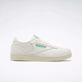 The Reebok Club C Shoes - Big Kids feature a white upper, green and red logo accents, beige sole, and classic low-top '80s style. Shown in profile on a light background, they're perfect for junior boys wanting timeless Reebok sneakers.