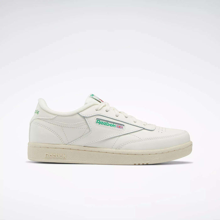 The Reebok Club C Shoes - Big Kids feature a white upper, green and red logo accents, beige sole, and classic low-top '80s style. Shown in profile on a light background, they're perfect for junior boys wanting timeless Reebok sneakers.