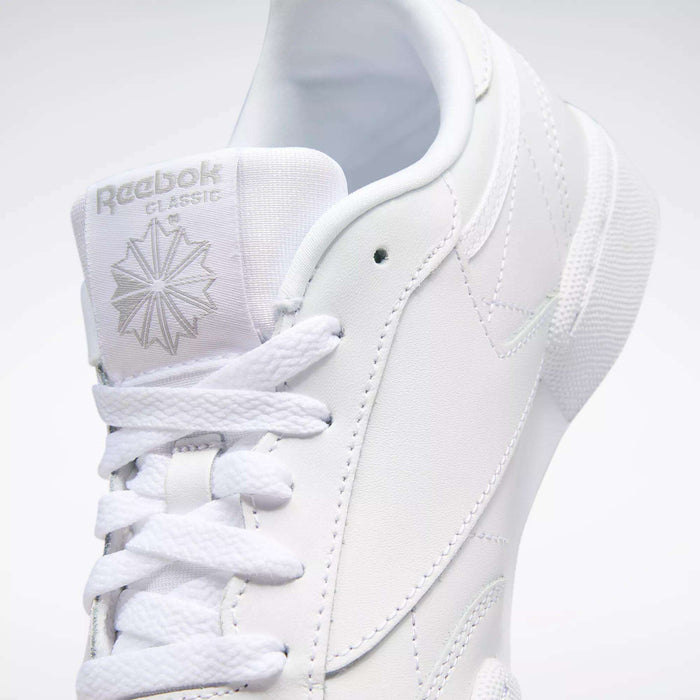 Close-up of the Kids' Club C Shoes - Grade School by Reebok, featuring white soft leather uppers, detailed stitching, laces, a branded tongue with logo and starburst, plus a high-abrasion rubber outsole.