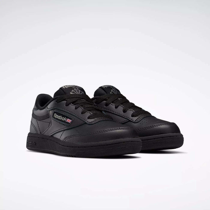 A pair of black Reebok Kids' Club C Shoes for little kids with laces, leather upper, Reebok branding, and Union Jack flag on the side are displayed on a light background.