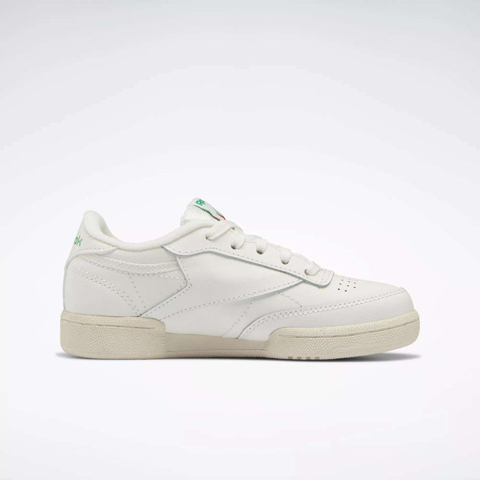 The Reebok Kids' Club C Shoes - Preschool are white low-top sneakers with a beige sole, subtle stitching, and small green logo accents on the heel and tongue, inspired by '80s style and shown against a light background.