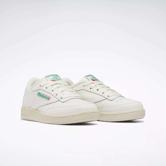The Reebok Kids' Club C Shoes - Preschool, seen at an angle on a white background, feature off-white uppers with green and red logo accents, capturing classic '80s style for a timeless, retro-inspired look.