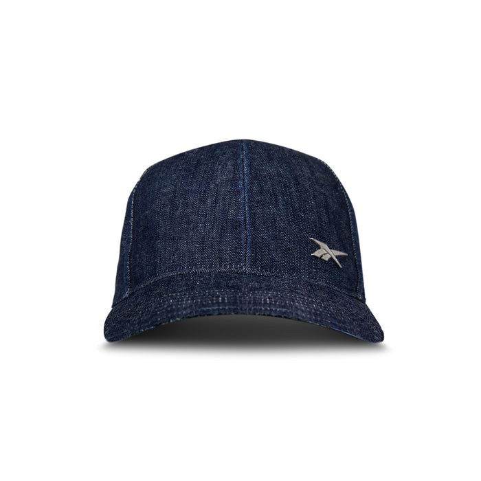 The Reebok Denim Badge Cap is a dark blue premium denim hat featuring visible stitching, a small silver logo on the lower right front, and a Speedwick sweatband, shown against a white background.