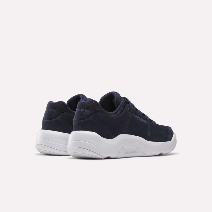 A pair of Reebok DMX Comfort+ Classic walking shoes in navy blue with white soles, made from premium leather, displayed from the back and side on a light background.